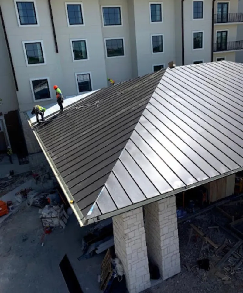 Crew installing standing seam metal roof panels on a commercial project in Ranson corporation